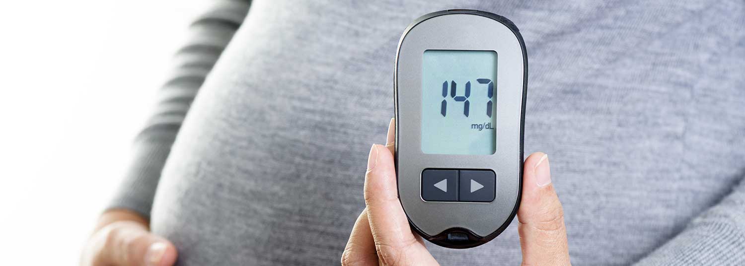 Pregnant woman holding blood sugar monitor