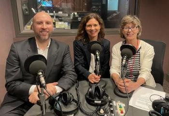 Jason Falvey and Kelly Westlake pose with microphones next to NPR host Sheilah Kast