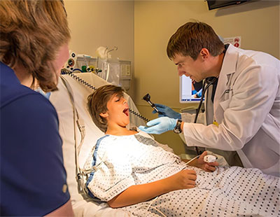 Mom with son who is being examined by a doctor