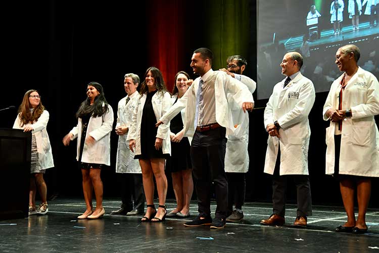 Student celebrating while they receive their white coats