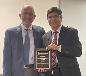 Dr. Melhem presenting Dr. Gandhi with an award